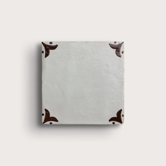 square zellige tile in a grid format with brown handpainted fleur pattern.