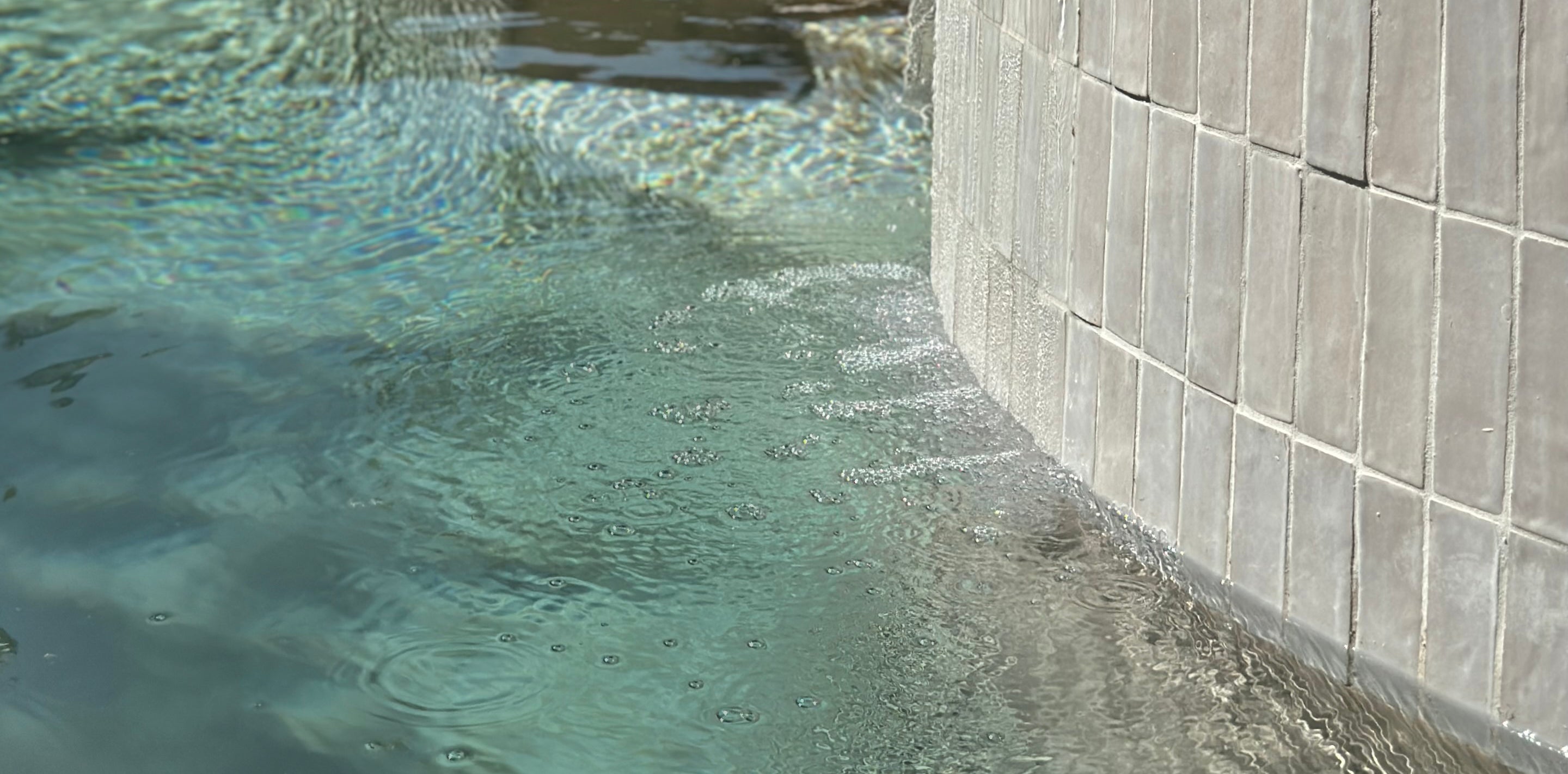 Pool tile close-up with waterline detail and textured gray swimming pool tiles