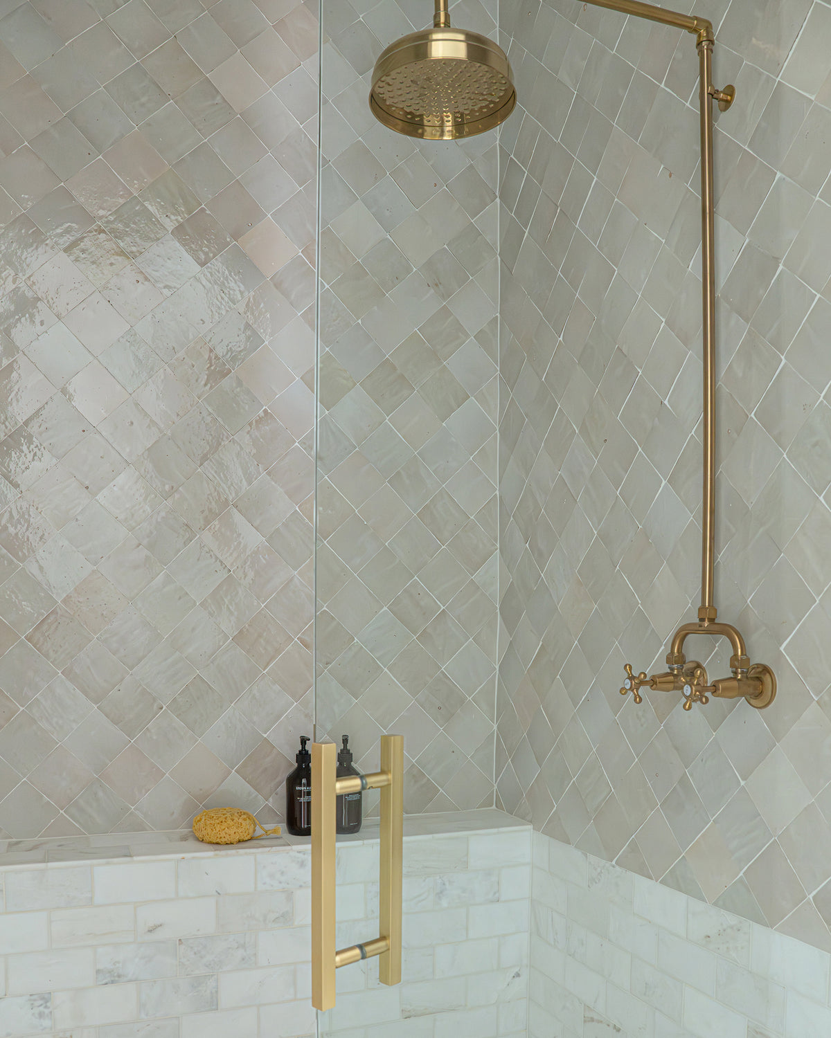 zellige tile installed on shower wall with brass fixtures