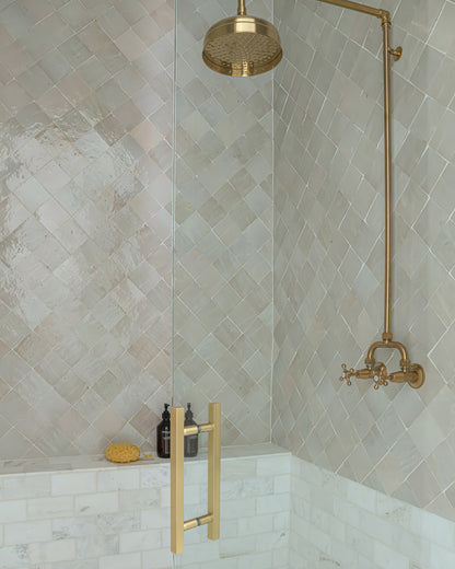 zellige tile installed on shower wall with brass fixtures
