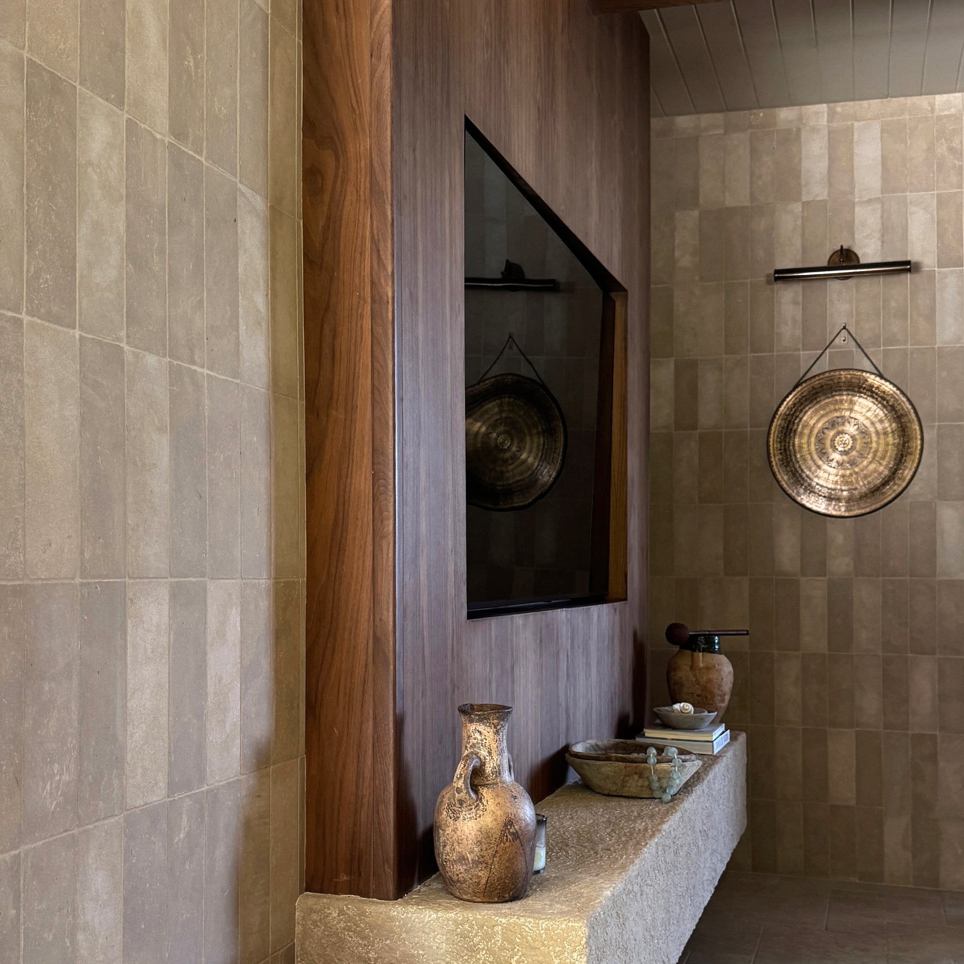 Living Room interior with limestone tiled walls, a wooden shelf, and decorative items.