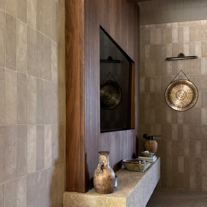 Living Room interior with limestone tiled walls, a wooden shelf, and decorative items.