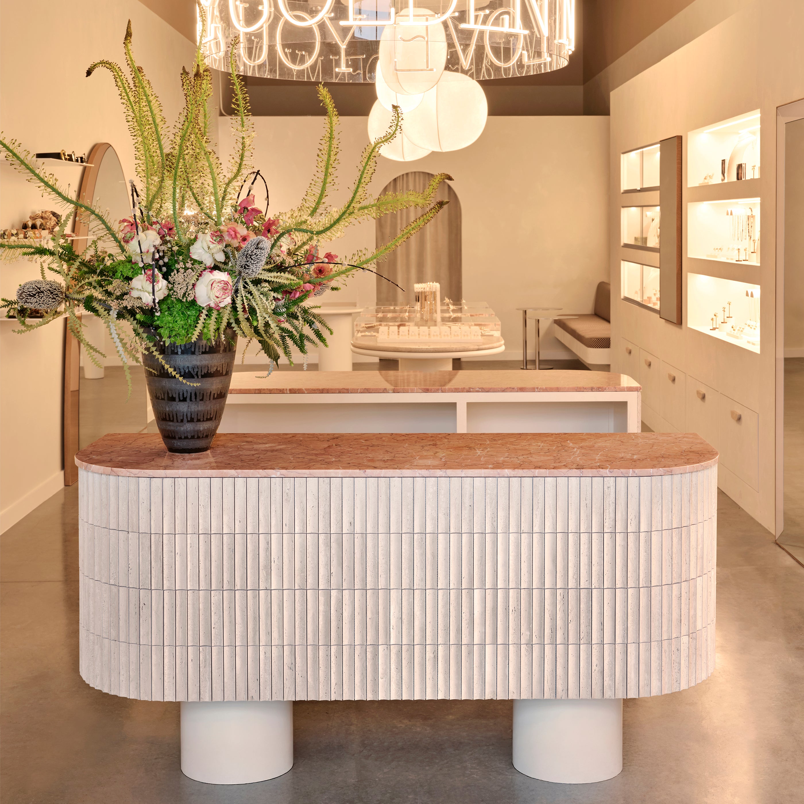 Modern reception desk with floral arrangement & beige travertine tile in a stylish interior setting