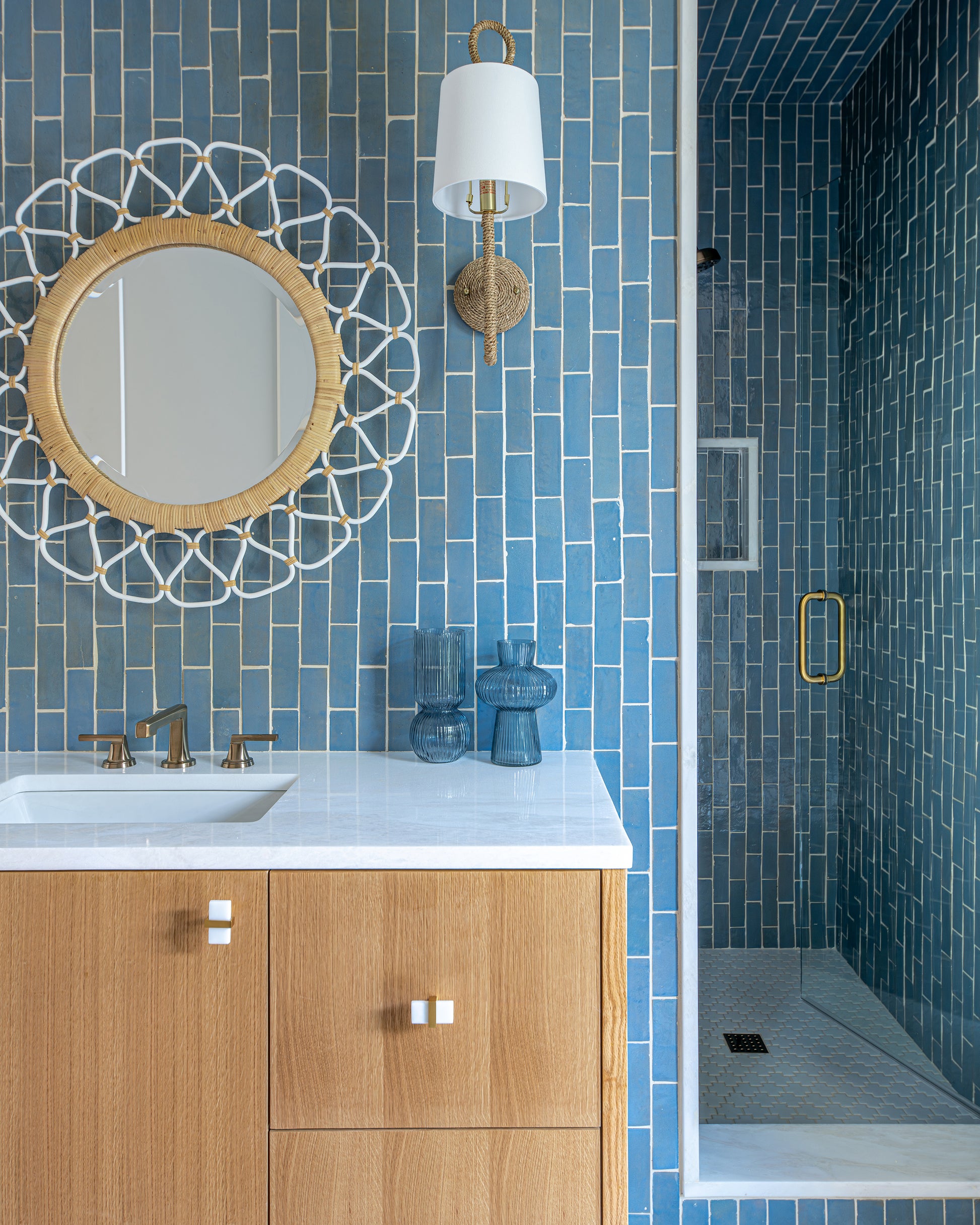 Bathroom with blue zellige tiled walls, wooden vanity, and decorative mirror.