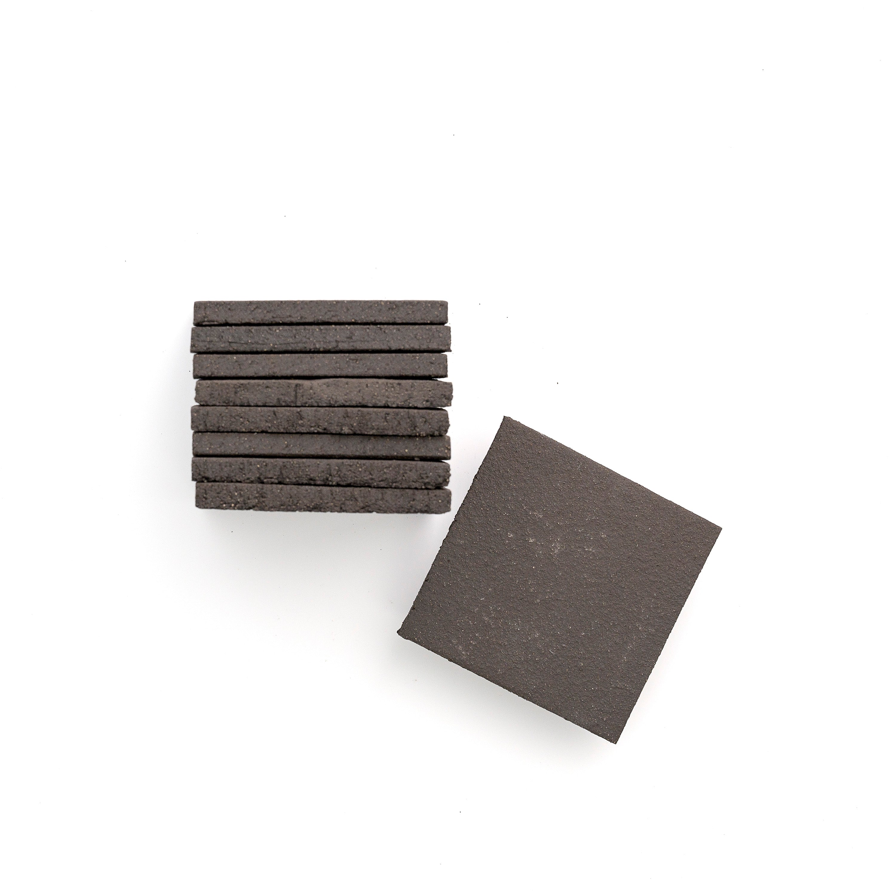 Stack of black terracotta square tiles on a white background