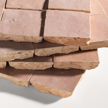 Stack of blush zellige stone tiles on a white background