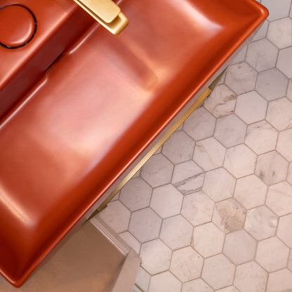 Copper sink with gold faucet on a hexagon marble tiled bathroom floor