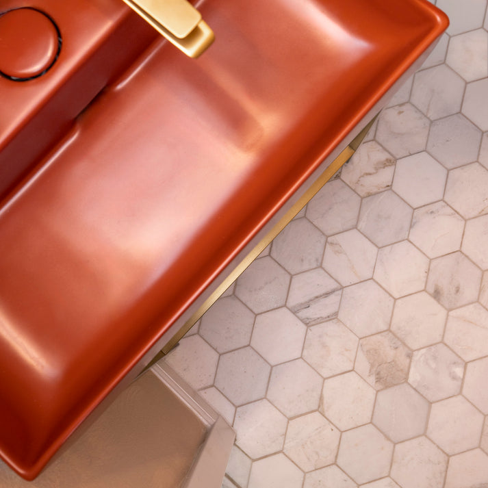 Copper sink with gold faucet on a hexagon marble tiled bathroom floor