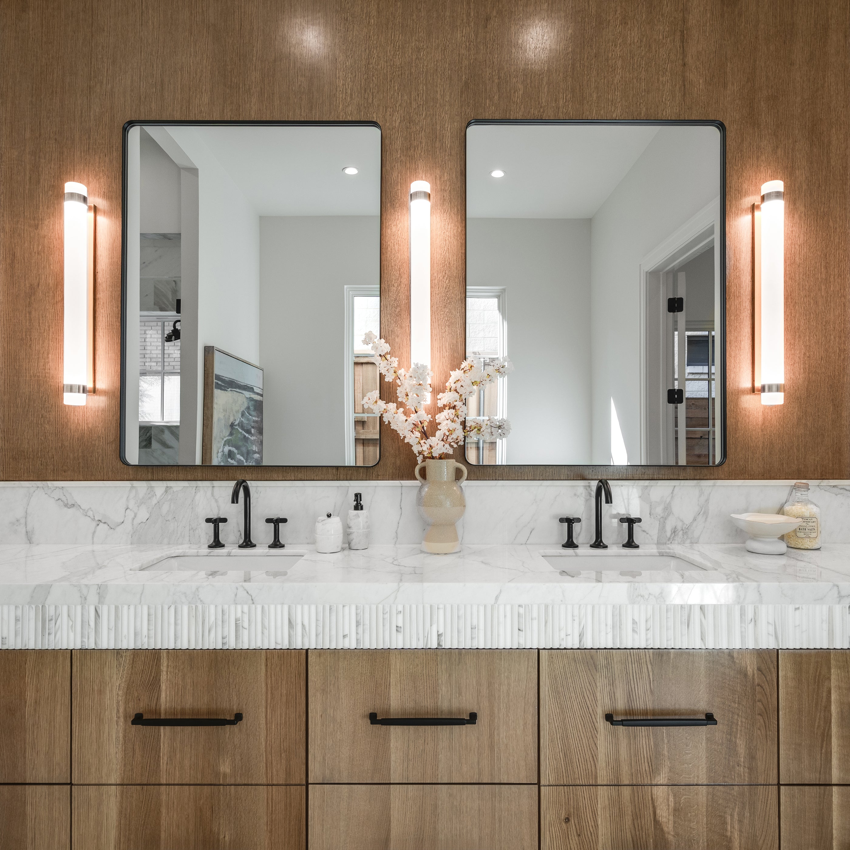 Bathroom vanity with double sink, mirrors, and decorative elements. Calacatta gold marble pencial mosaic on vanity.