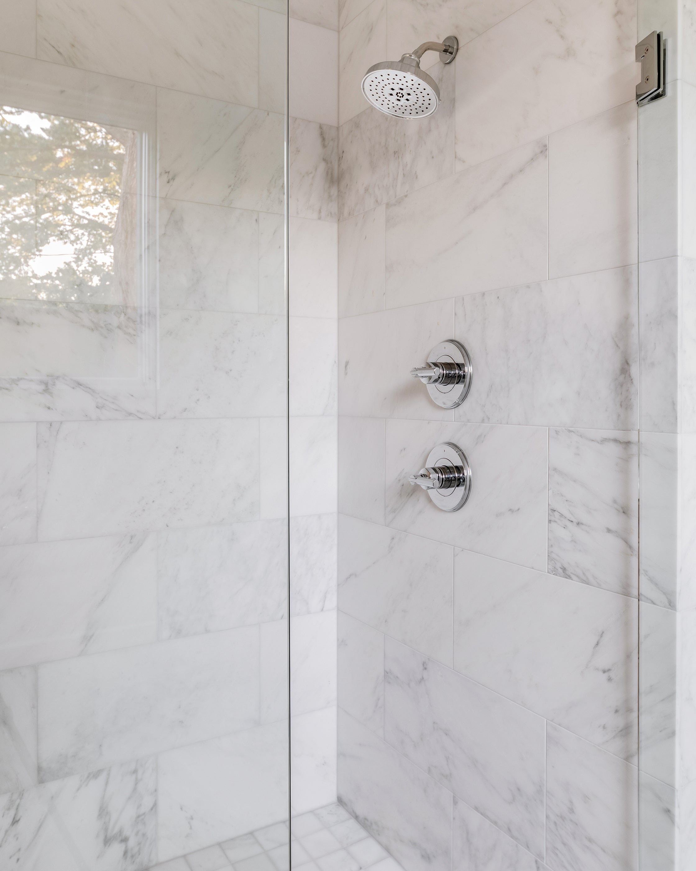 Modern shower setup with casablanca carrara marble walls and chrome fixtures