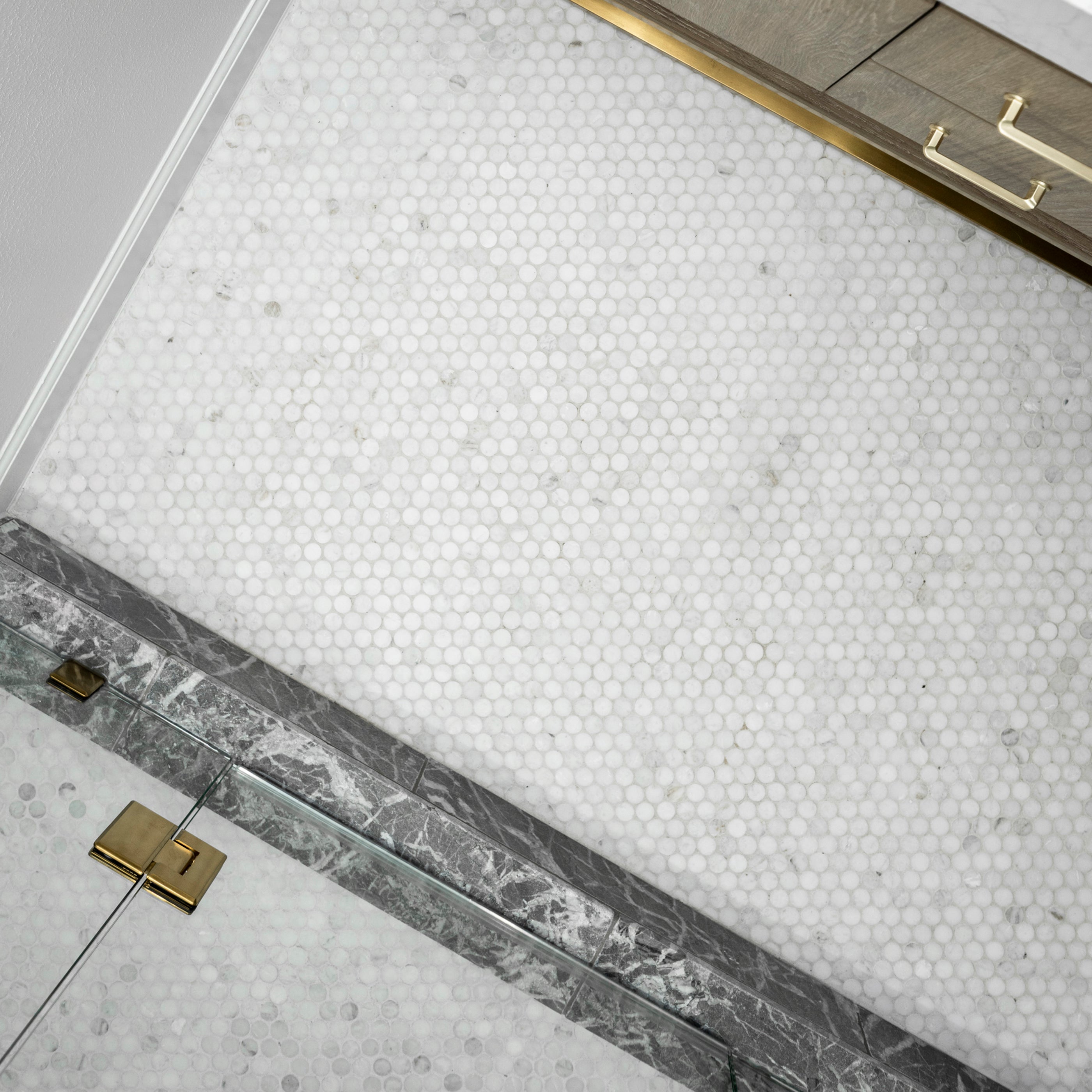 Close-up of a marble tiled bathroom floor with a geometric pattern and metallic border.