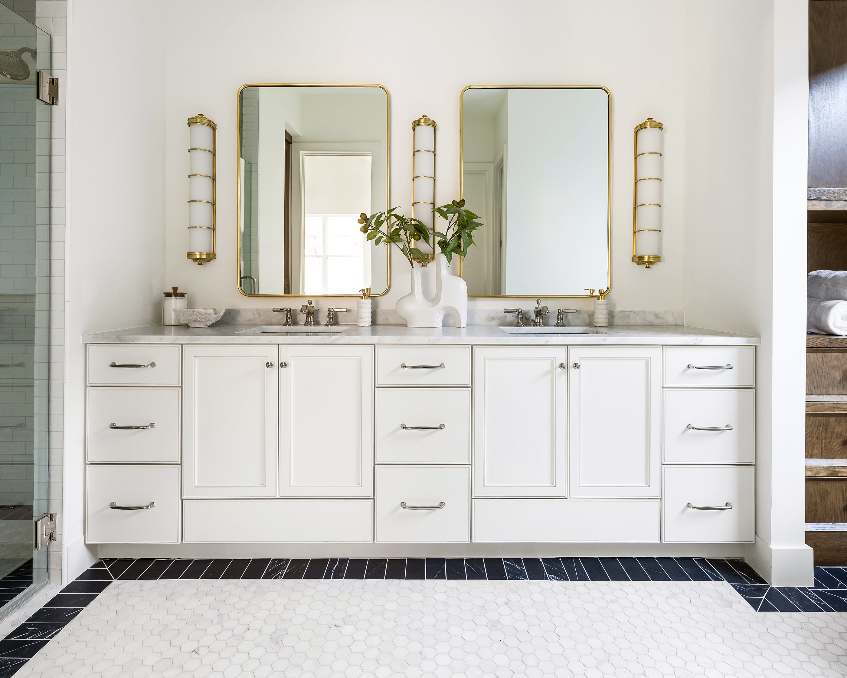 Bathroom with white vanity, mirrors, and decorative elements. Casablanca carrara hexagon tile flooring.