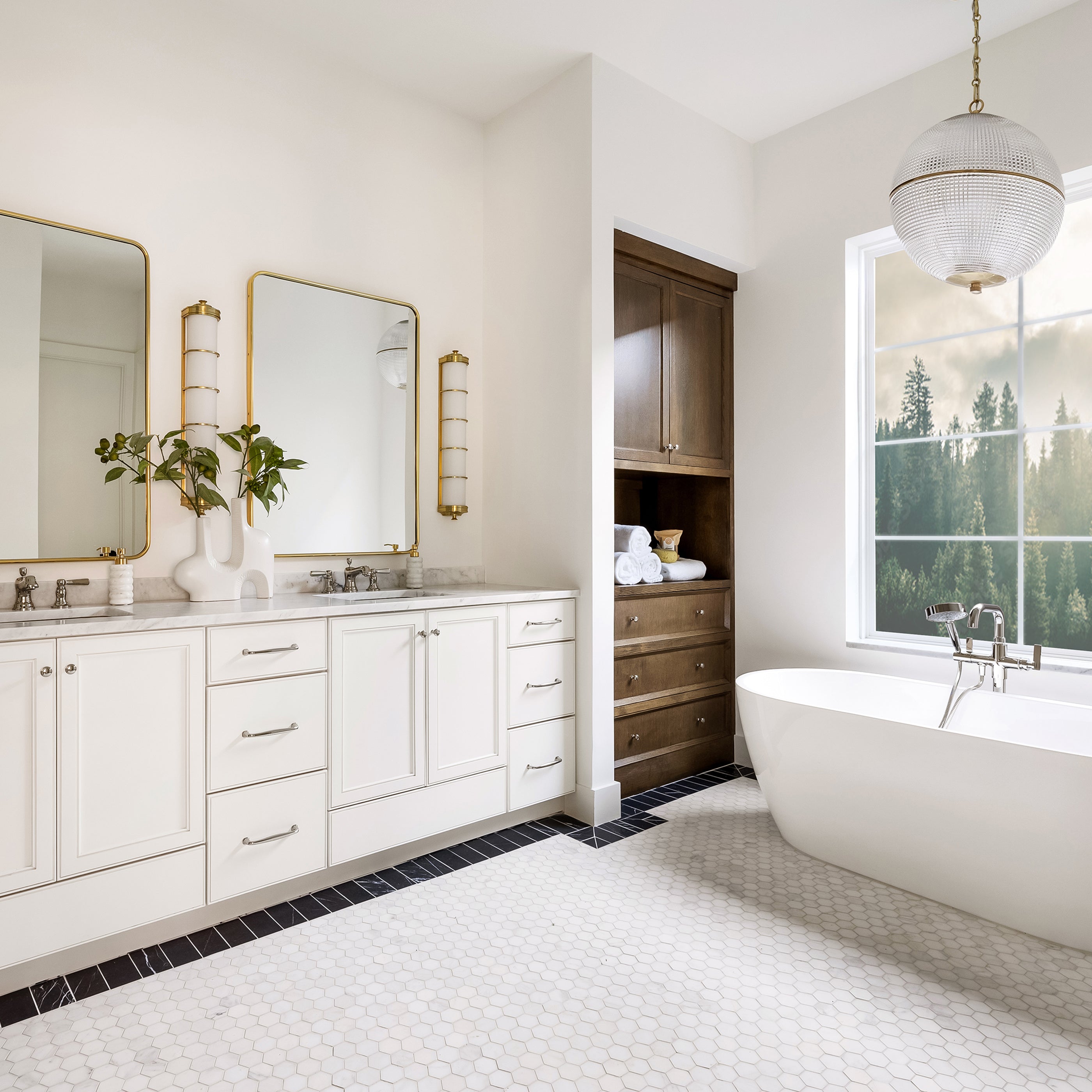Modern bathroom with white vanity, freestanding bathtub, large window, and marble hexagon floor tile.