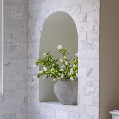 Decorative vase with flowers in a niche against a casablanca carrara marble wall.
