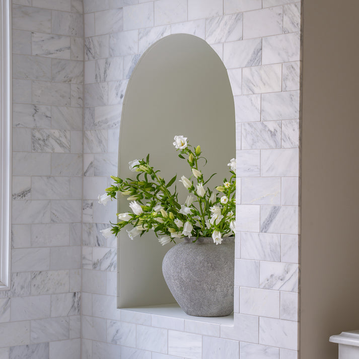 Decorative vase with flowers in a niche against a casablanca carrara marble wall.