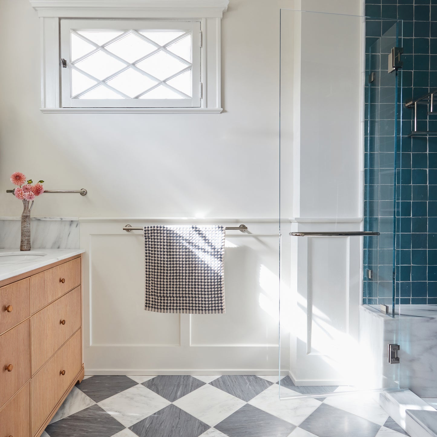 Bathroom interior with wooden vanity, checkered marble floor, and shower area.