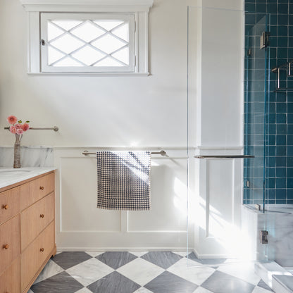 Bathroom interior with wooden vanity, checkered marble floor, and shower area.