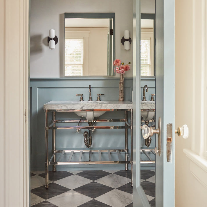 Bathroom with marble vanity, checkered marble floor, and floral arrangement.