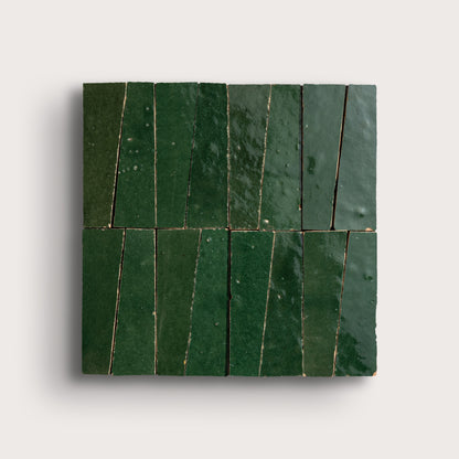 Green zellige trapezoid tiles arranged in a pattern on a light gray background