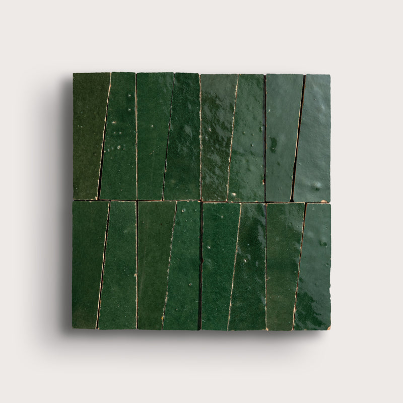 Green zellige trapezoid tiles arranged in a pattern on a light gray background