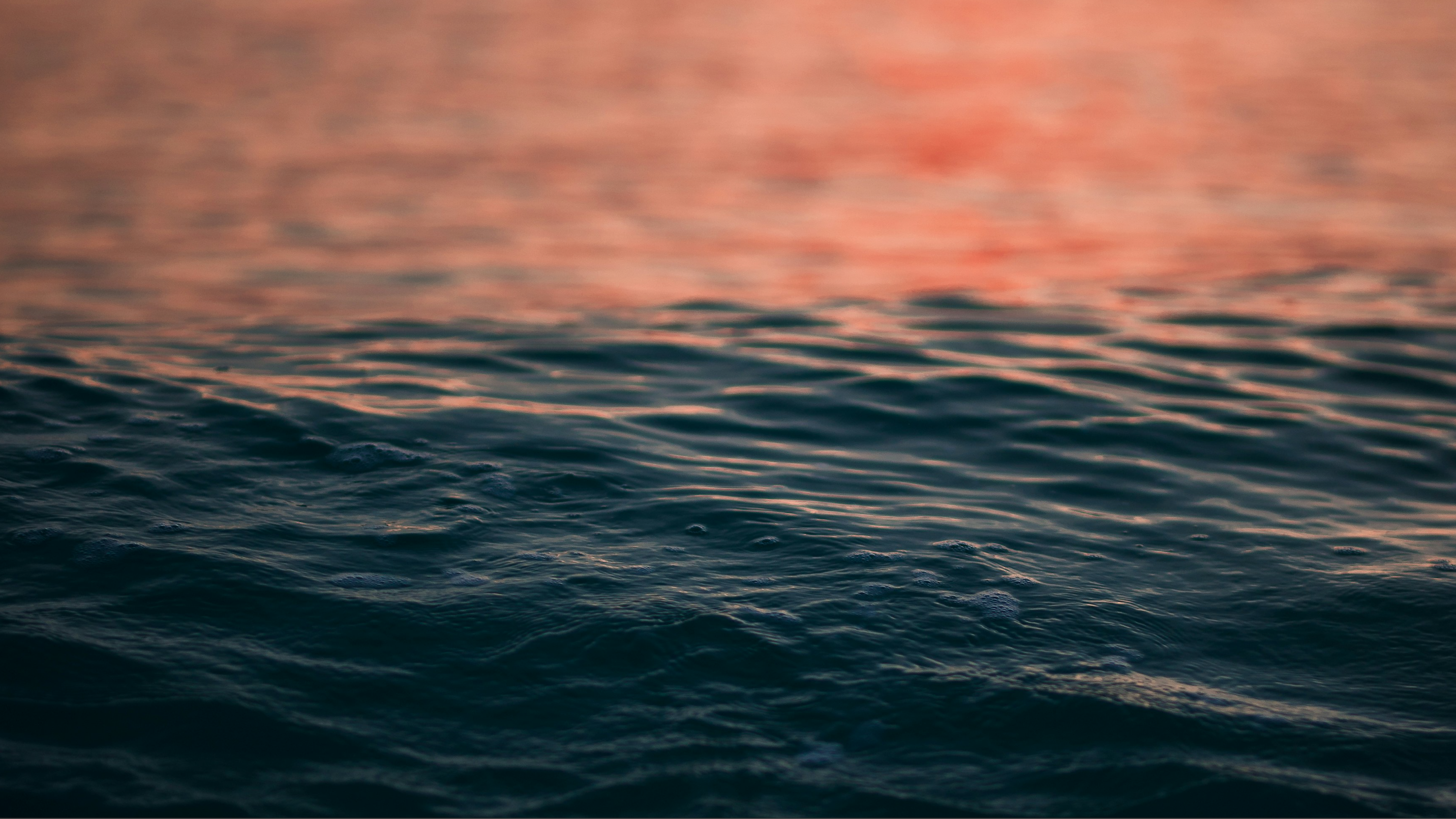 Waves on a body of water with a sunset reflection.