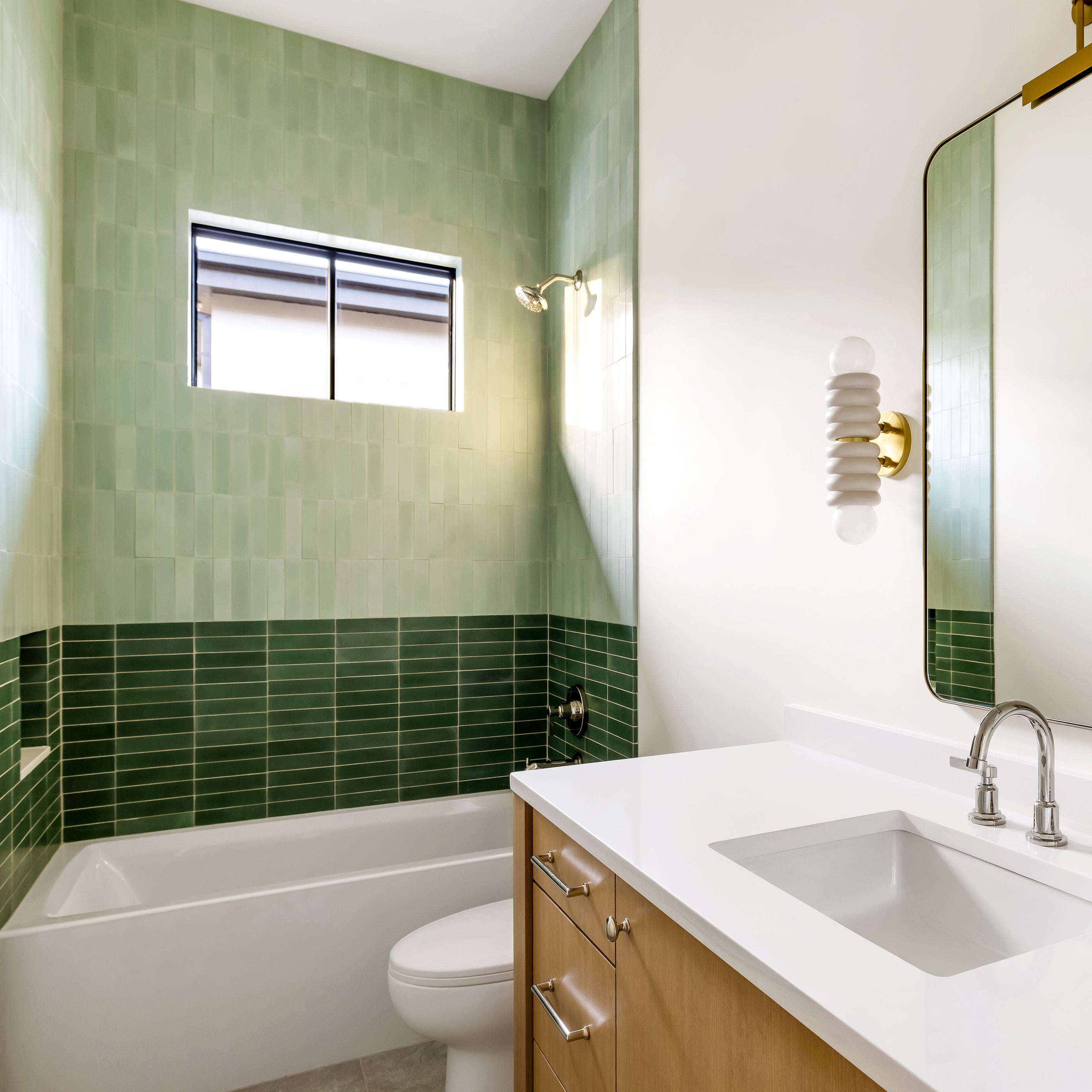 Modern bathroom with green cement tiled walls, white countertop, and wooden vanity.