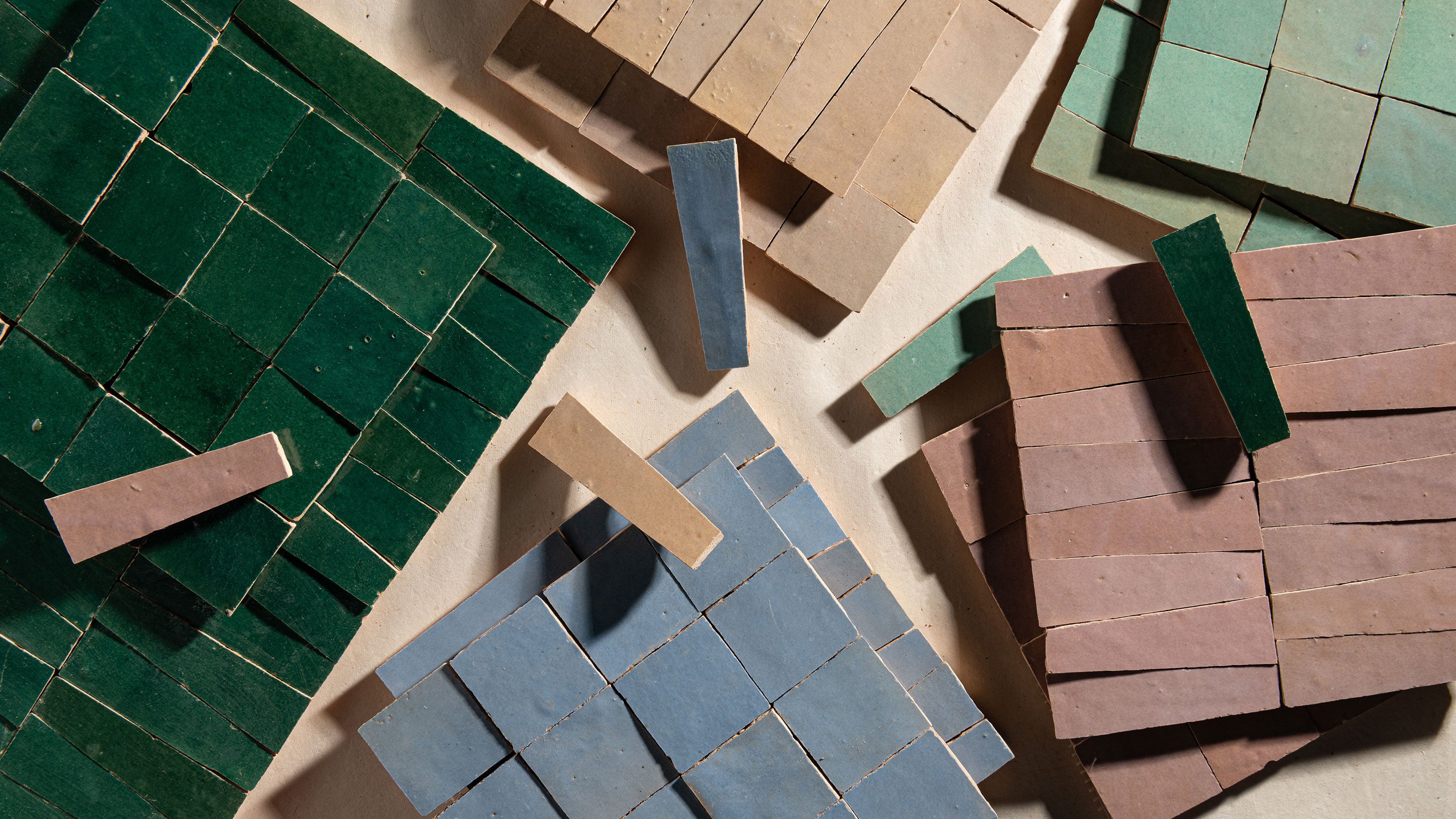 Colorful zellige tiles in various shapes and sizes on a neutral background