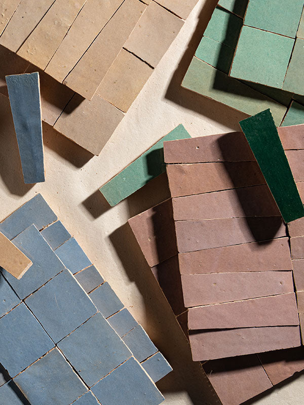 Collection of various colored zellige tiles on a neutral background