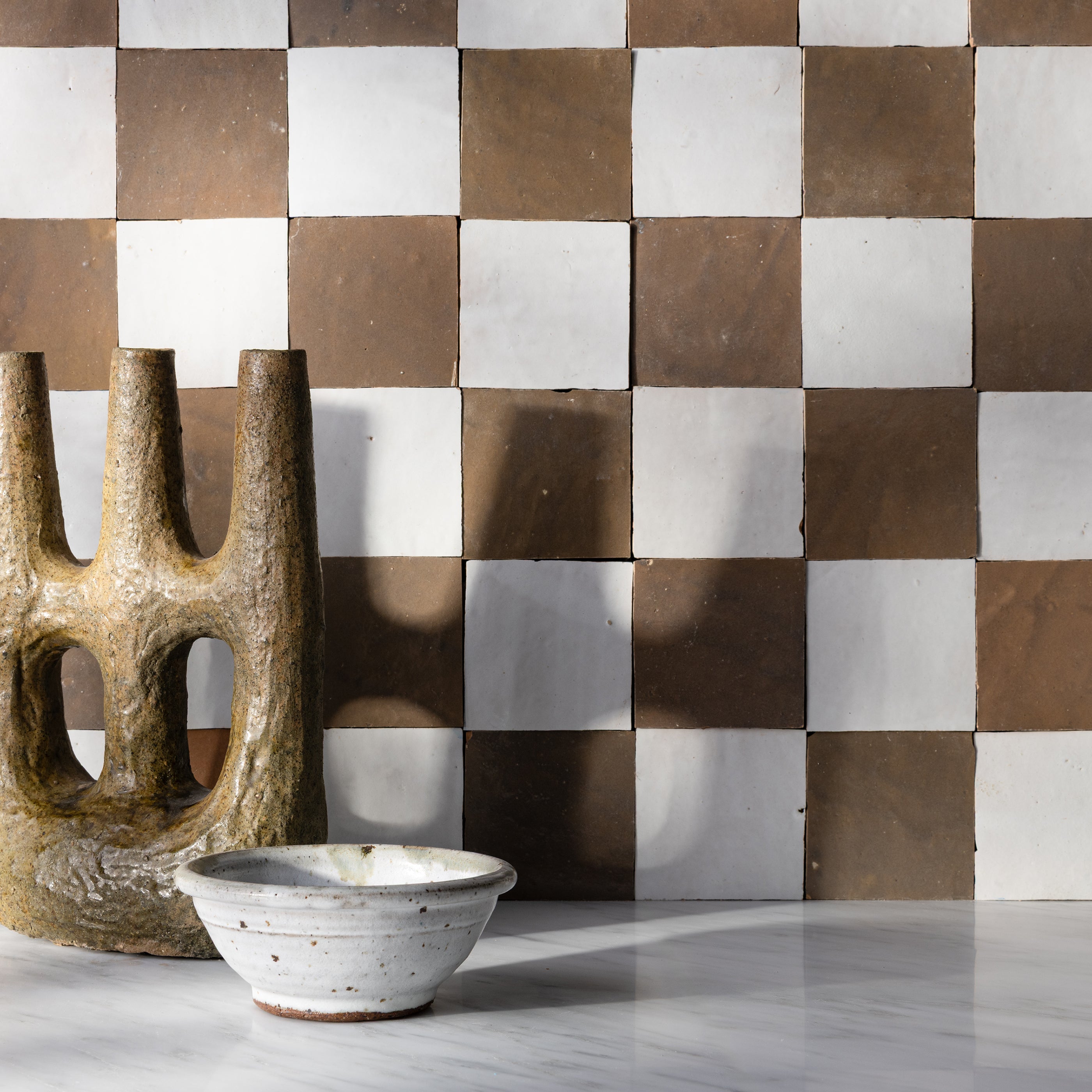 hazel and white checkerboard zellige backsplash tile in kitchen with sculpture in front