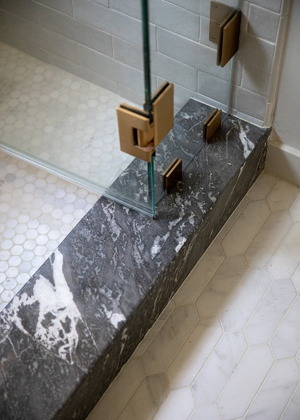 Marble shower with gold fixtures in a bathroom setting