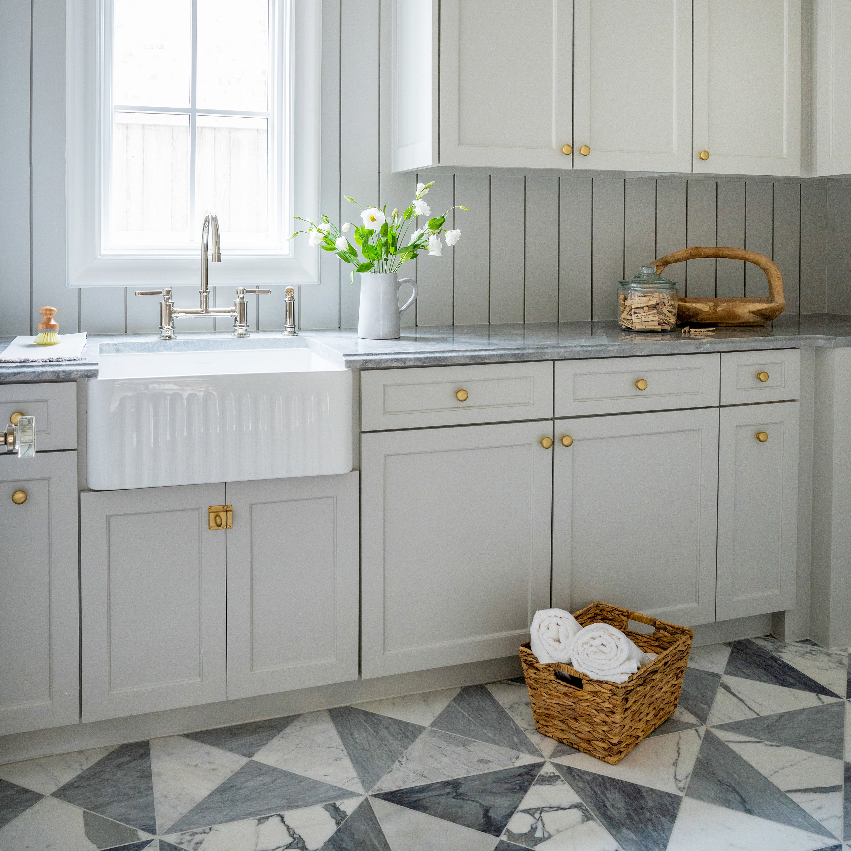 Modern kitchen with gray cabinets, white sink, and marble flooring.