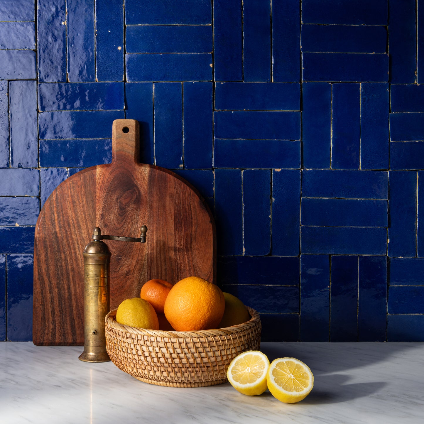 moroccan blue rectangle zellige tile as backsplash in kitchen with bowl of fruit and cutting board styled in front