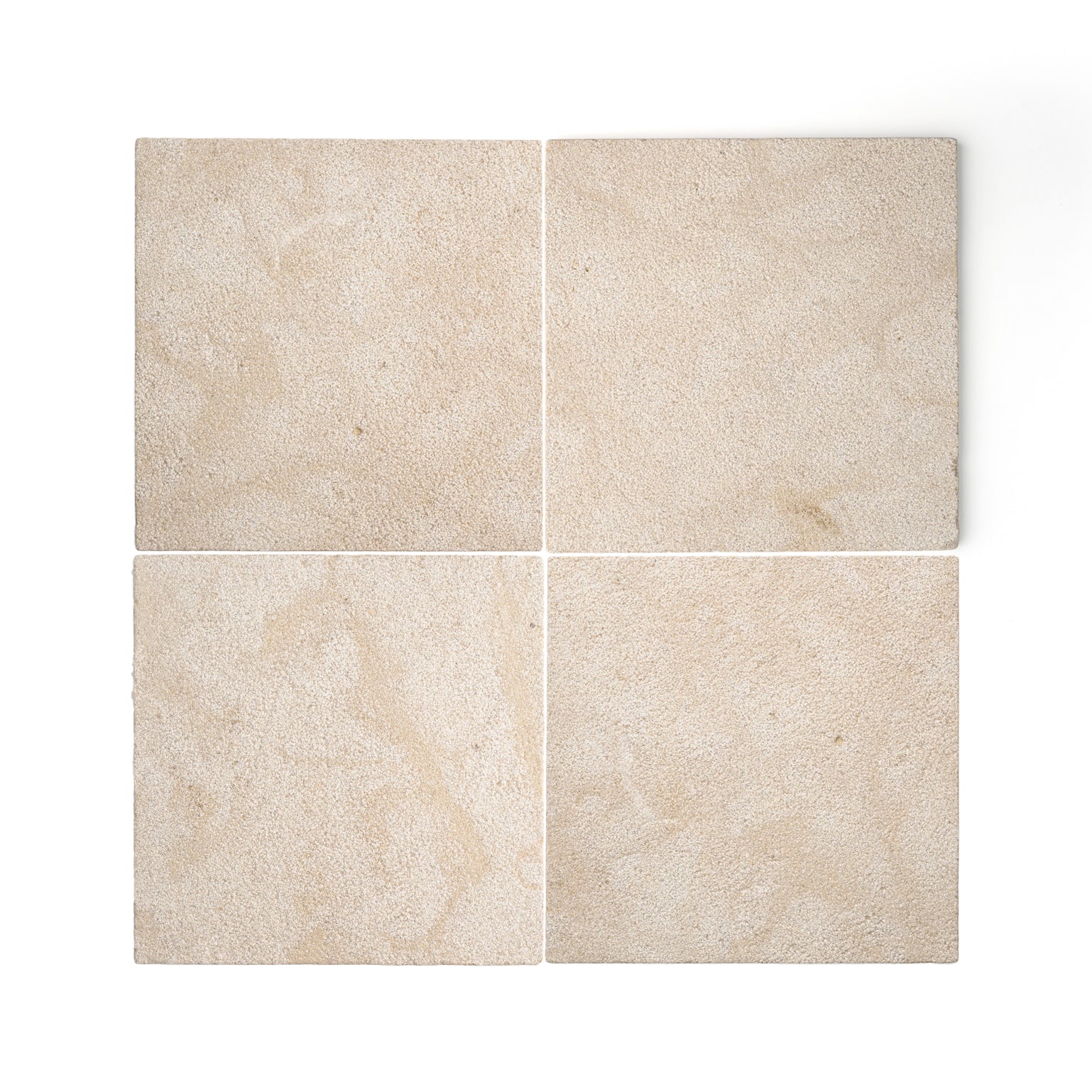 Four square beige limestone tiles arranged in a 2x2 grid on a white background, showing natural stone texture and subtle tonal variation.