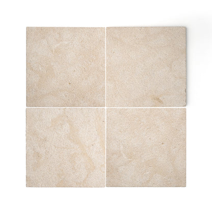Four square beige limestone tiles arranged in a 2x2 grid on a white background, showing natural stone texture and subtle tonal variation.
