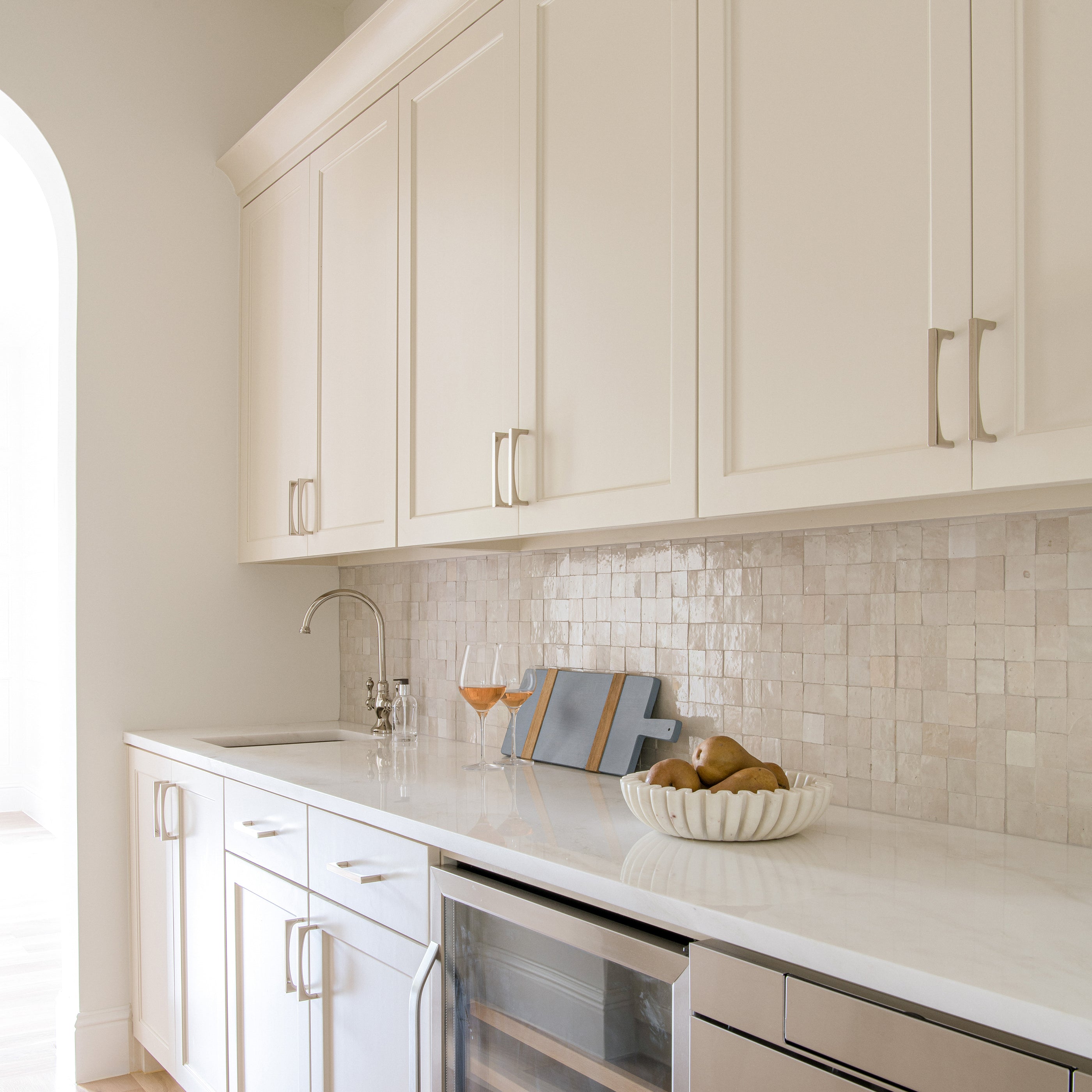 Modern kitchen with white cabinets, marble countertop, and zellige tiled backsplash.