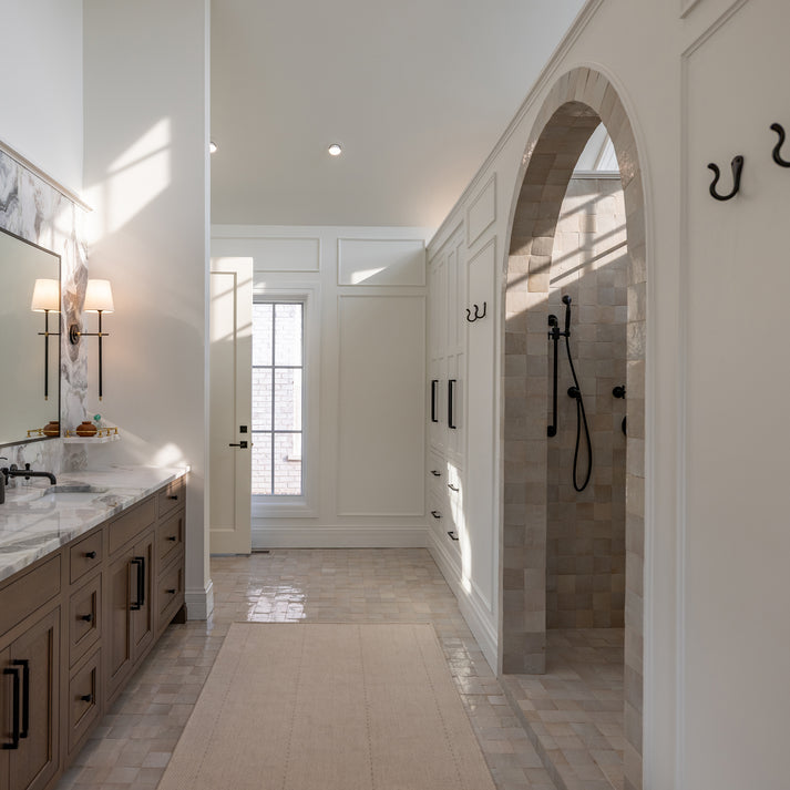 Luxurious bathroom with a walk-in shower, vanity, and large mirror. Off white zellige tile on the floor and walls of the shower.