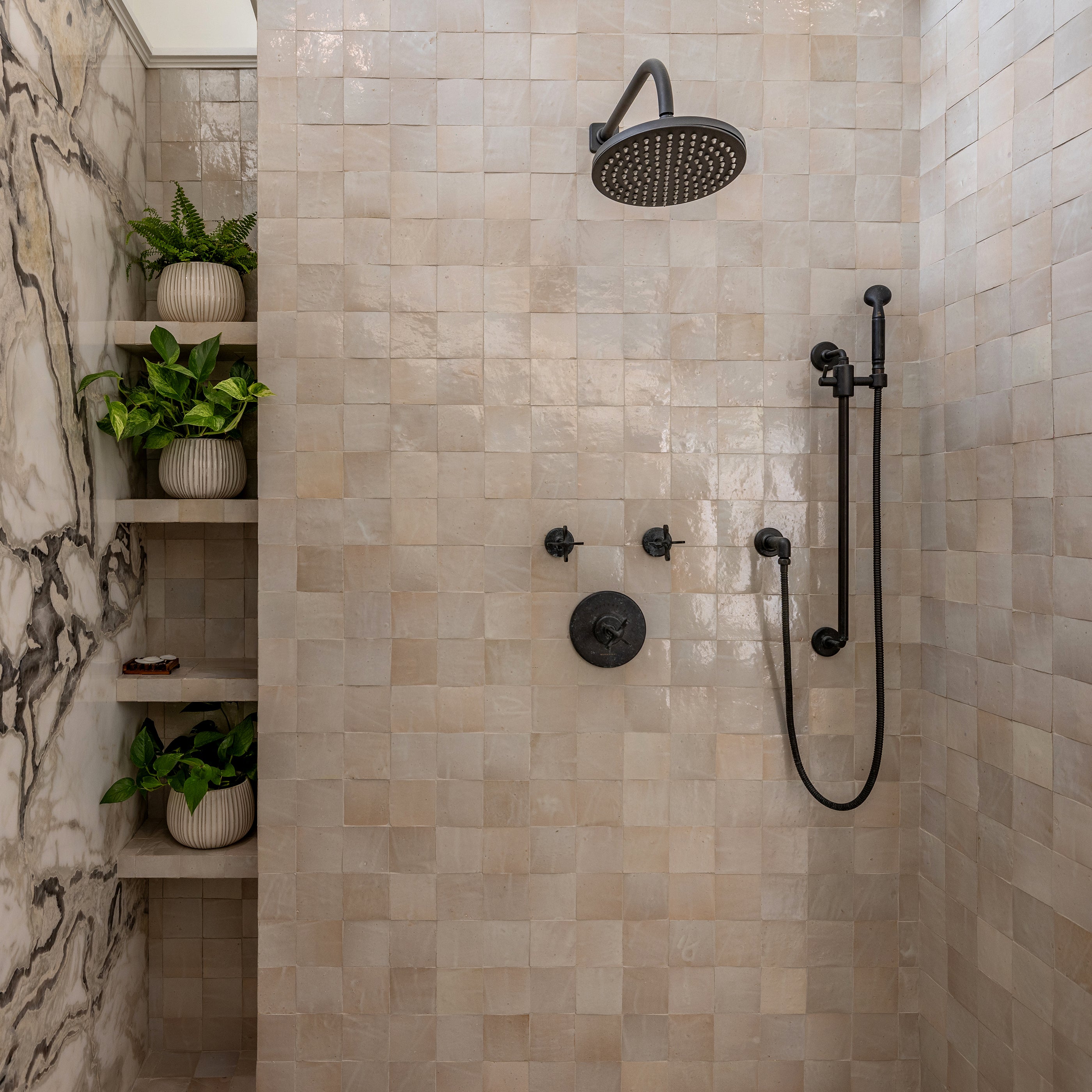 Luxurious bathroom with a walk-in shower. Off white zellige tile on the floor and walls of the shower.