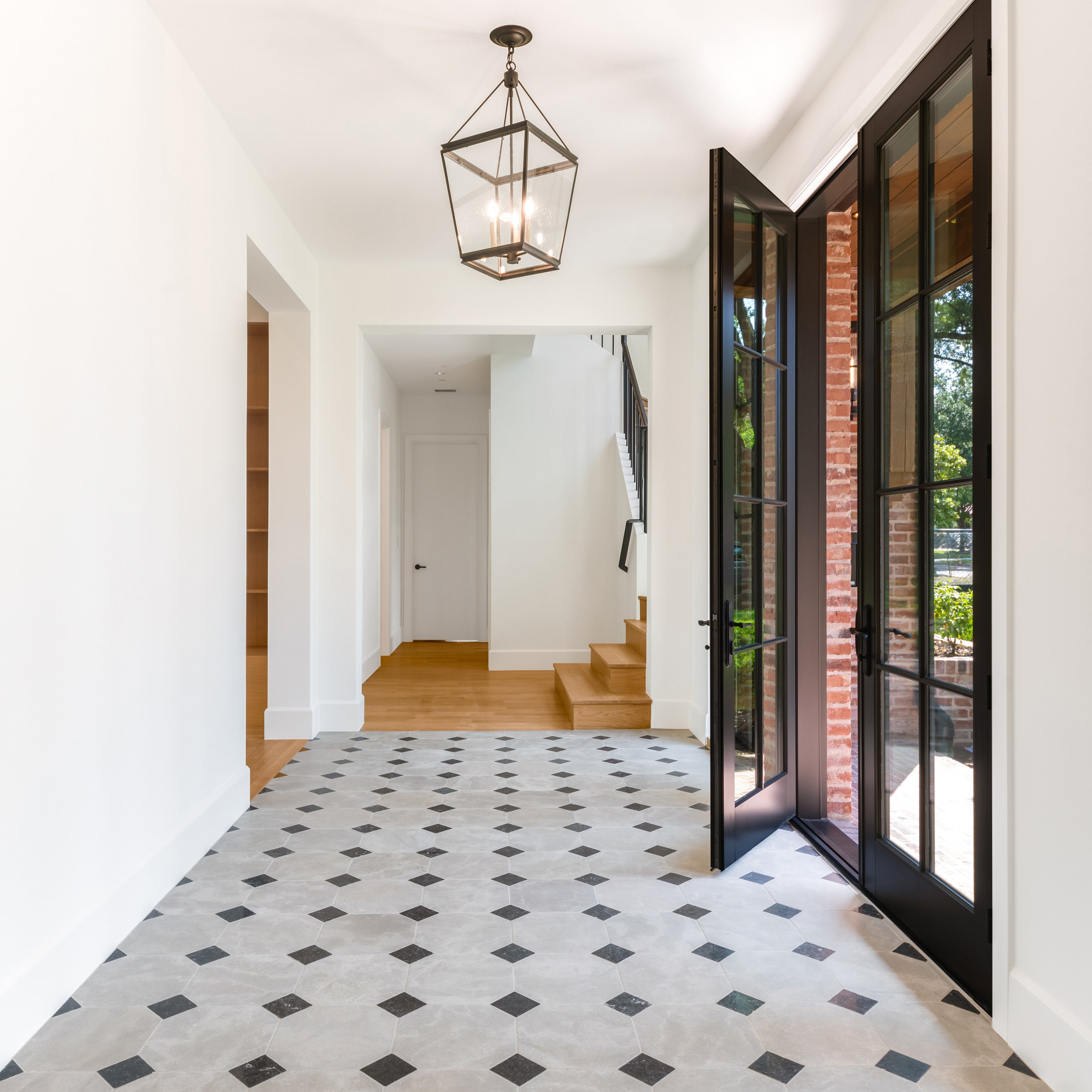 Modern interior with patterned limestone and marble tile, pendant light, and French doors.
