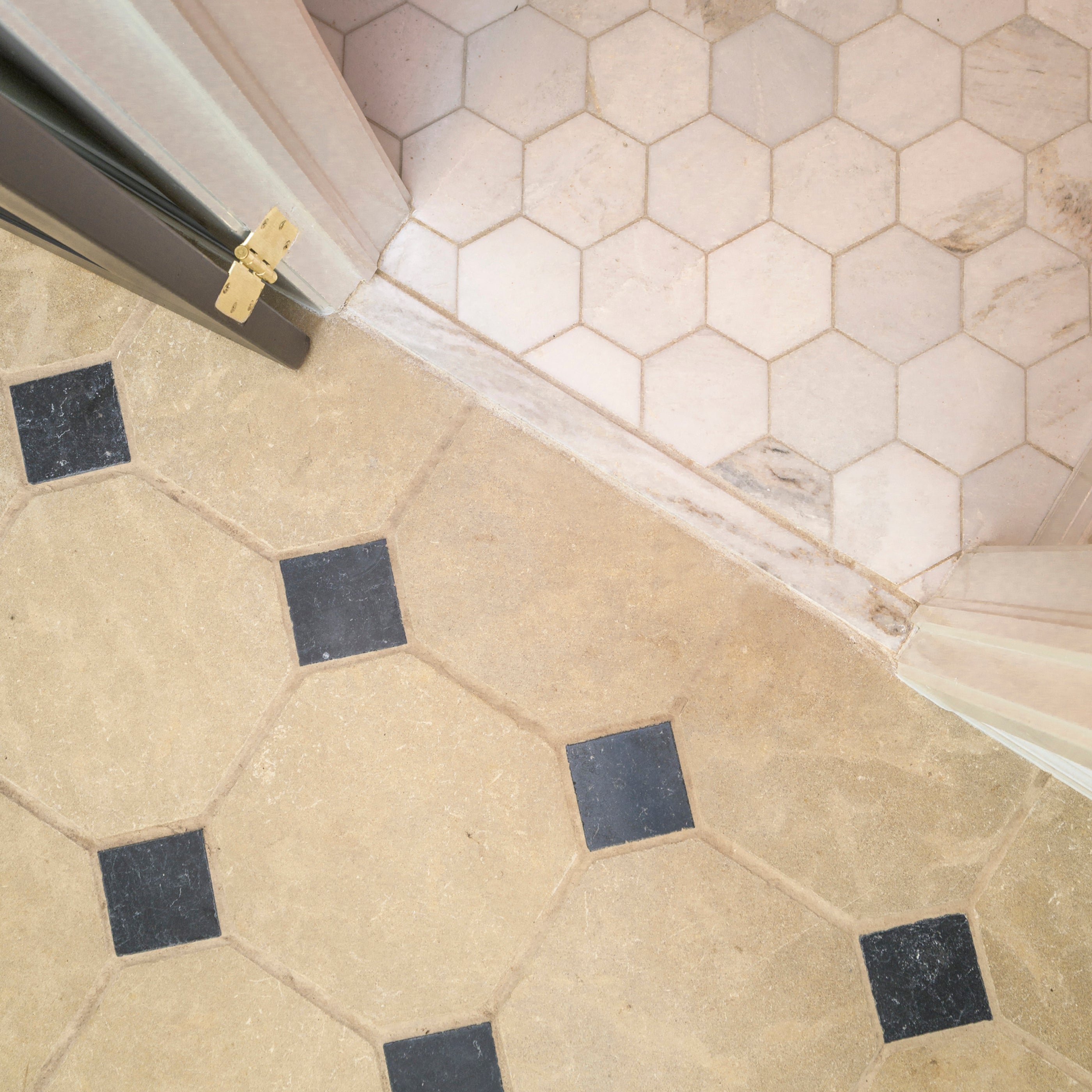 Close-up of a floor with limestone hexagonal tiles and a corner transition.
