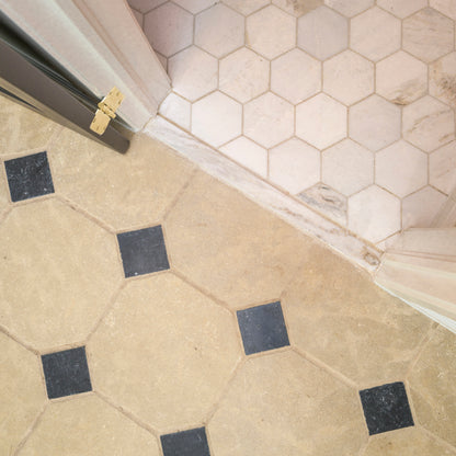 Close-up of a floor with limestone hexagonal tiles and a corner transition.