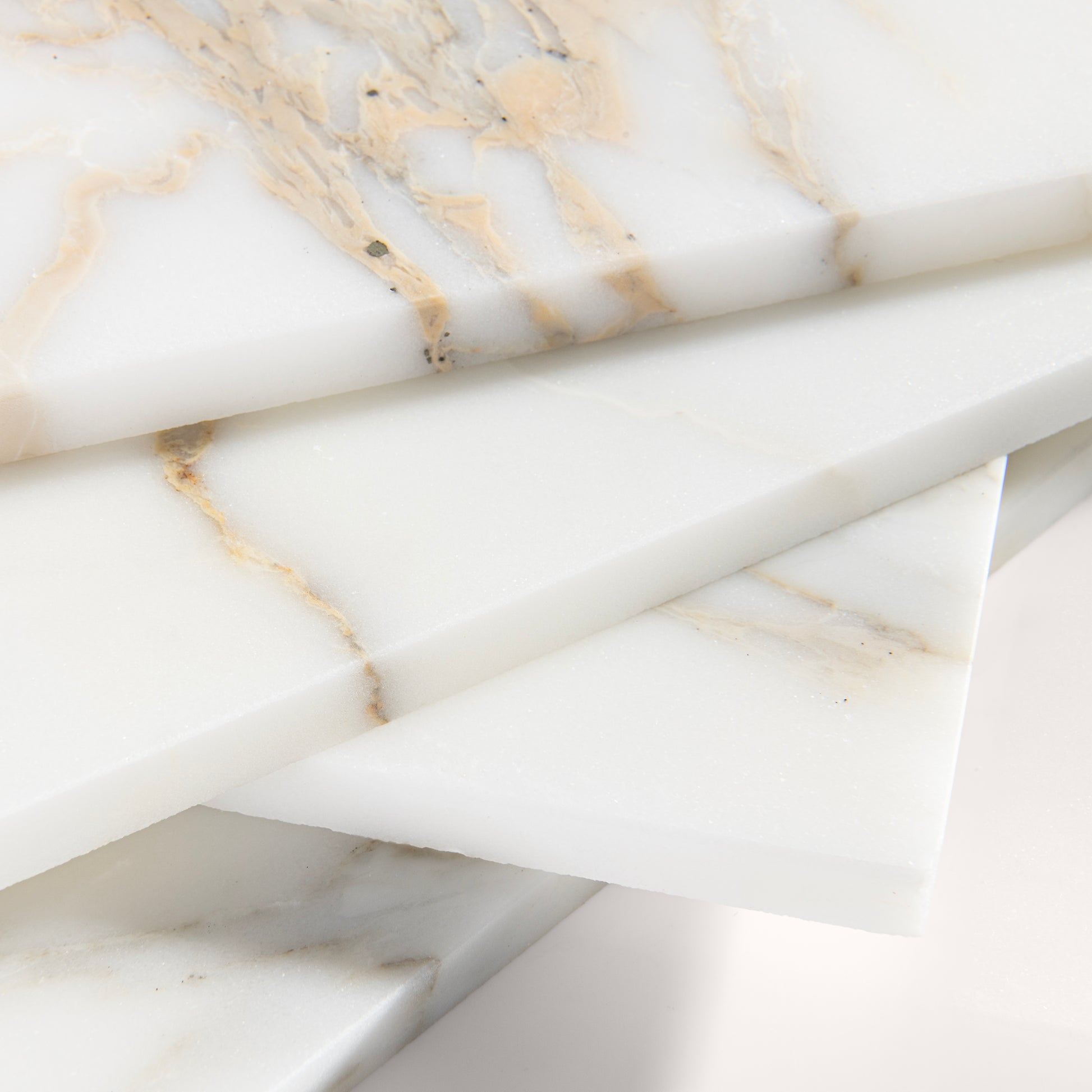 close up angle of calacatta gold Marble tiles on a light gray background