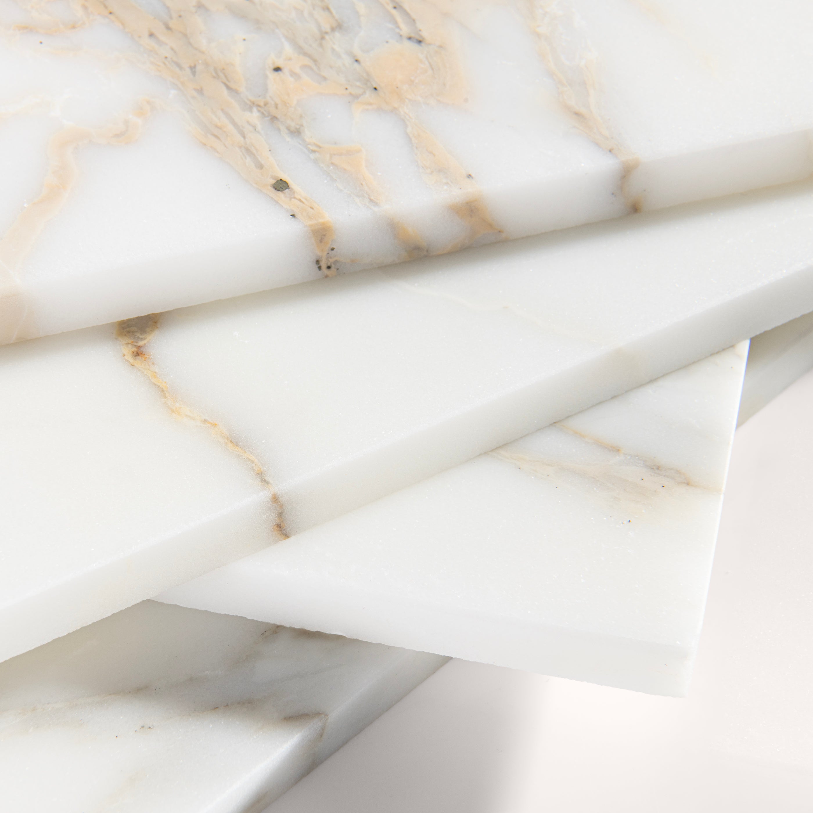 close up angle of calacatta gold Marble tiles on a light gray background