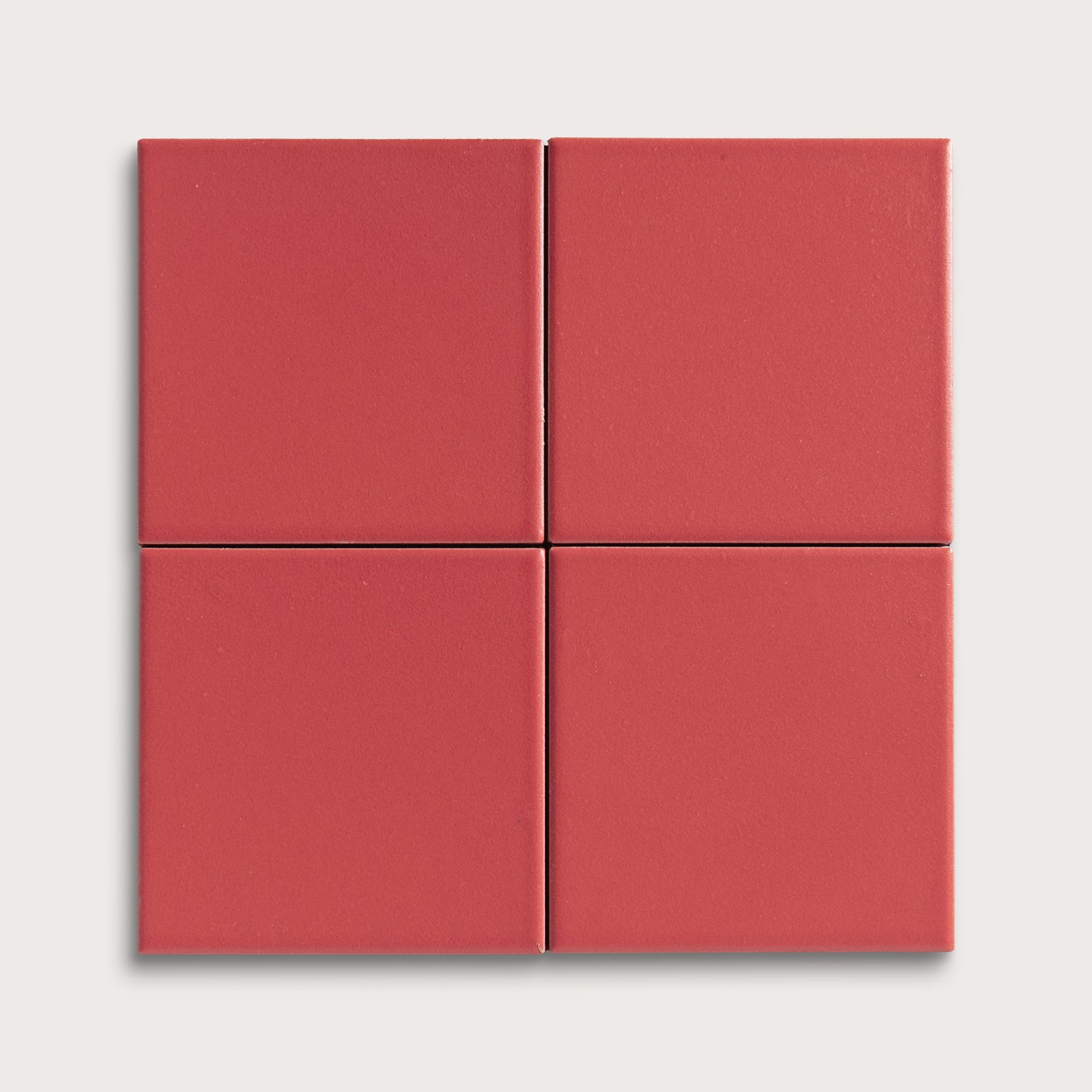 Four red square ceramic tiles on a light gray background