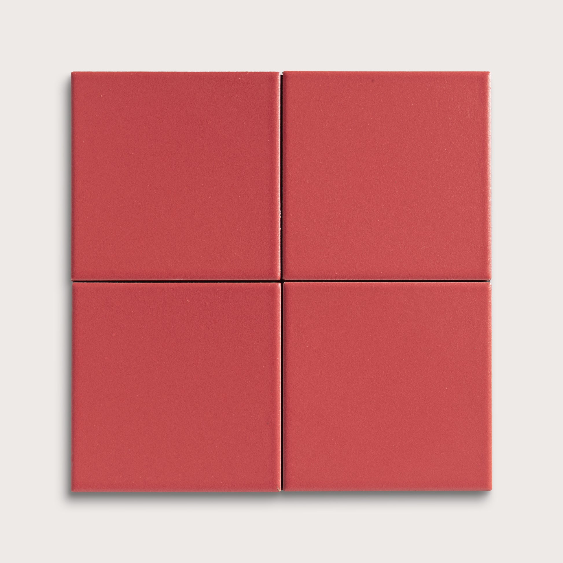 Four red square ceramic tiles on a light gray background