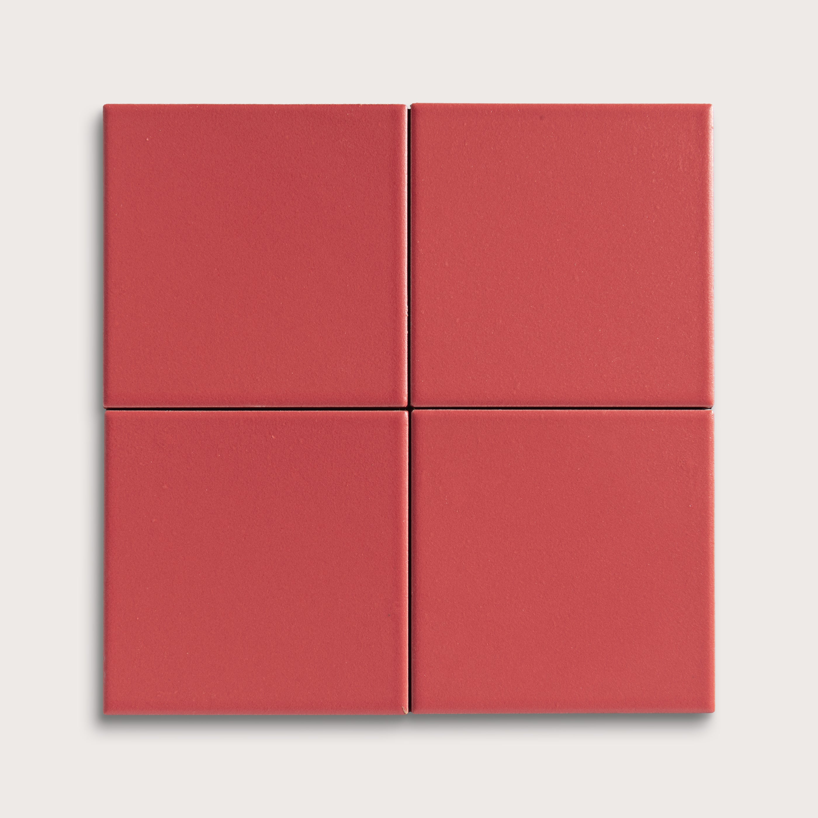 Four red square ceramic tiles on a light gray background