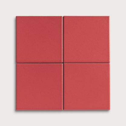 Four red square ceramic tiles on a light gray background
