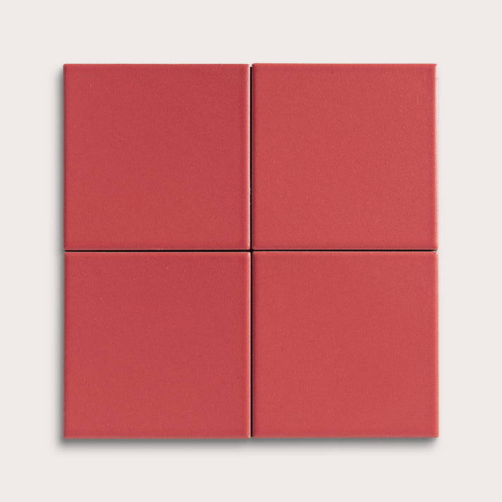Four red square ceramic tiles on a light gray background