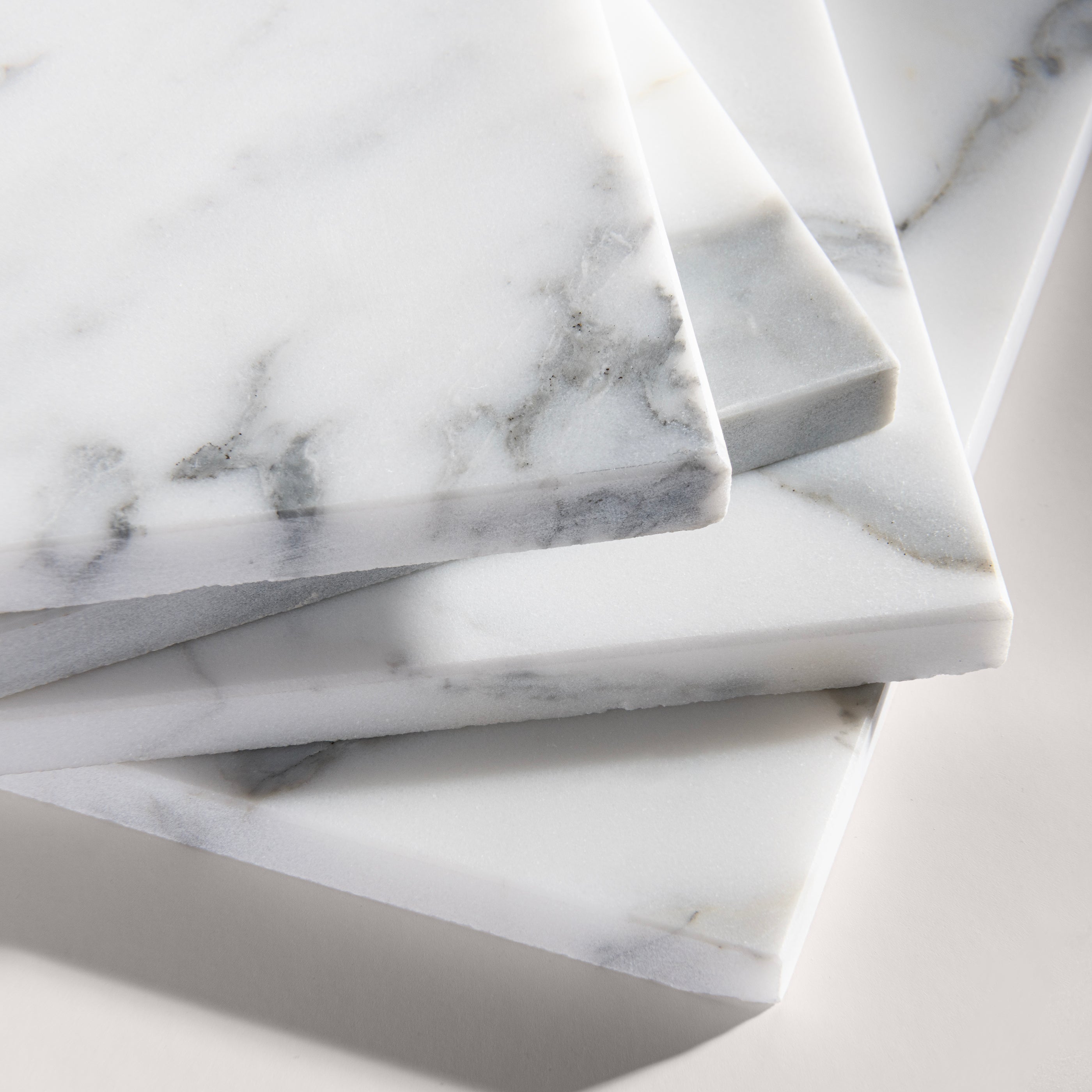 close up angle of italian statuary white and grey marble tiles  on a light gray background