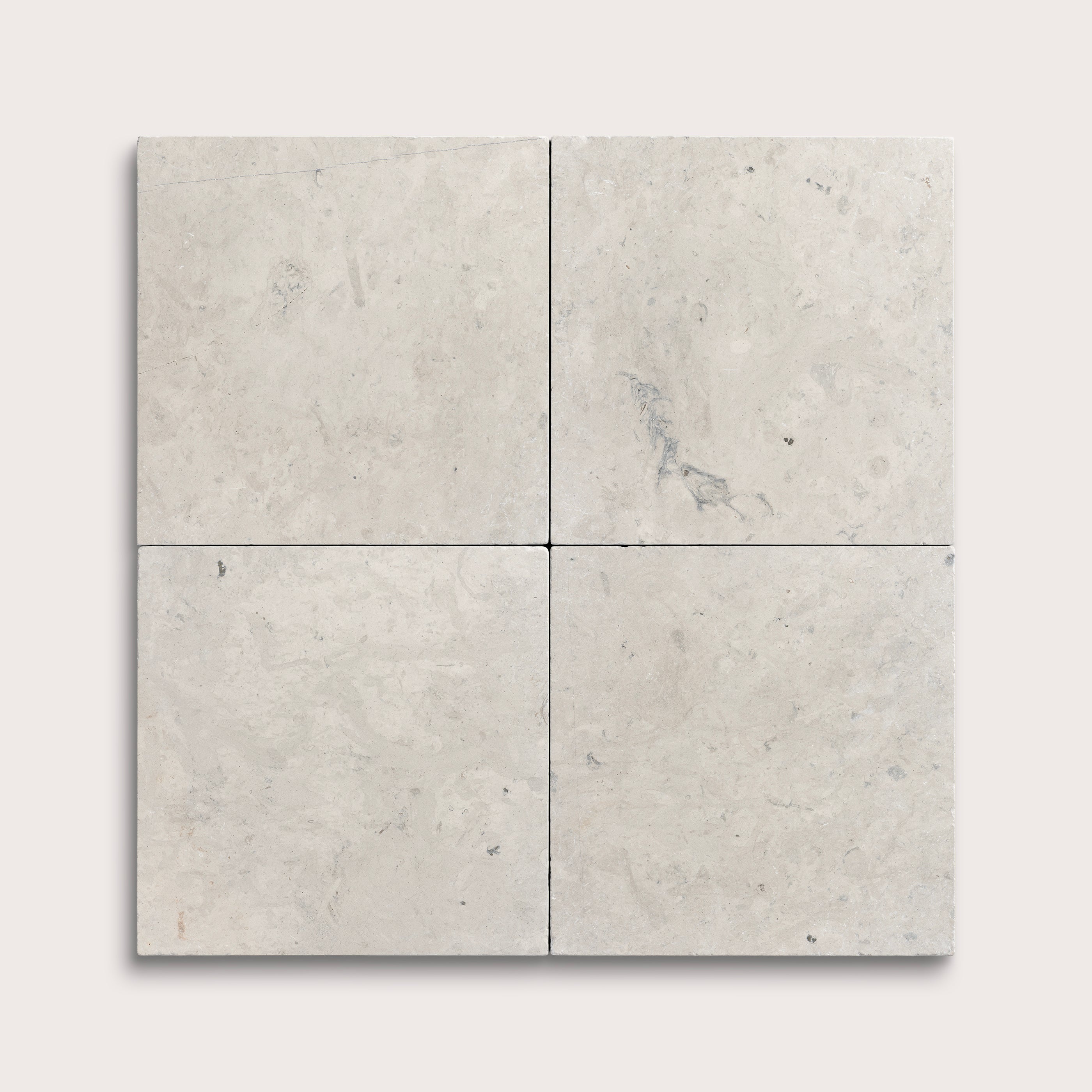 Four square limestone tiles with a light gray marble pattern on a white background