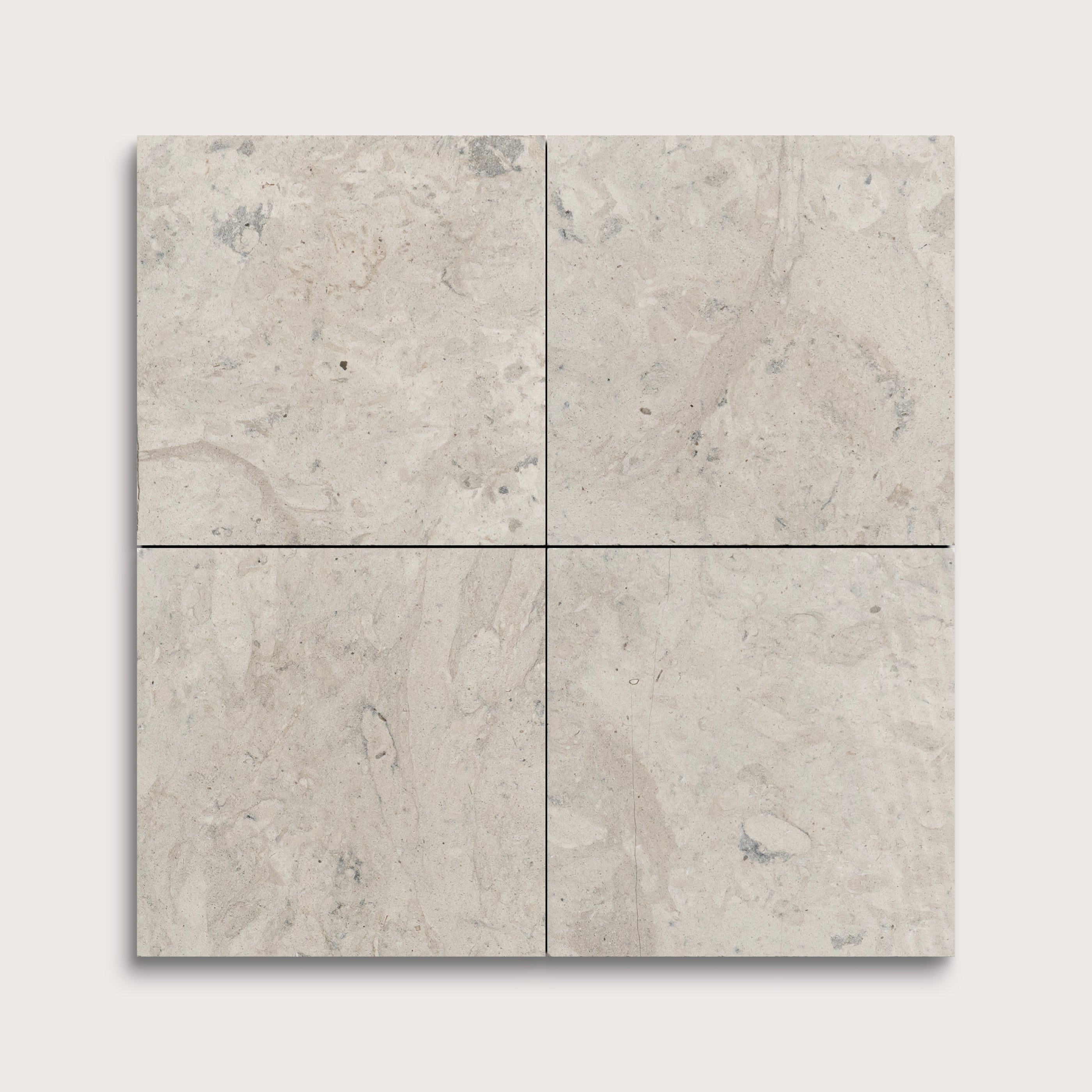 Four square tiles with a beige limestone pattern on a white background